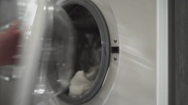 Vrouwelijke hand met getrouwde ring neemt WITTE KLEUREN uit wasmachine. Laden wasmachine. Laad kleren in de wasmachine. Laad kleding wasmachine. Wasgoed klaarmaken — Stockvideo