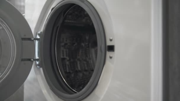 Vrouwelijke hand met getrouwde ring zet BLACK CLOTHES in de wasmachine. Laden wasmachine. Laad kleren in de wasmachine. Laad kleding wasmachine. Wasgoed klaarmaken — Stockvideo