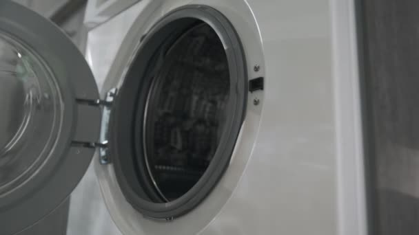 Female hand with married ring puts GREY CLOTHES from laundry machine. Loading washing machine. Load clothes to washer machine. Load clothes laundry washing machine. Preparing laundry washing — Stock Video