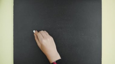 Üst Manzara. Kadın tahtaya tebeşirle LESSON 2 yazıyor..