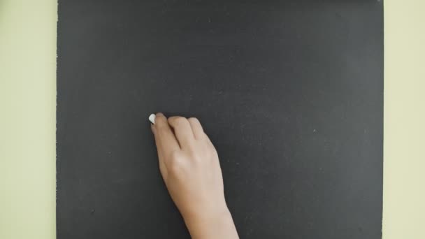 Bovenaanzicht. Vrouw schrijft het woord HOME met krijt op een schoolbord. — Stockvideo