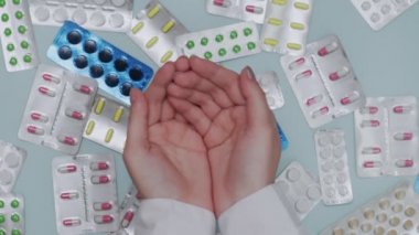 Kadın doktorların elleri arka planda kabarcıklar olan hapları yakalar.