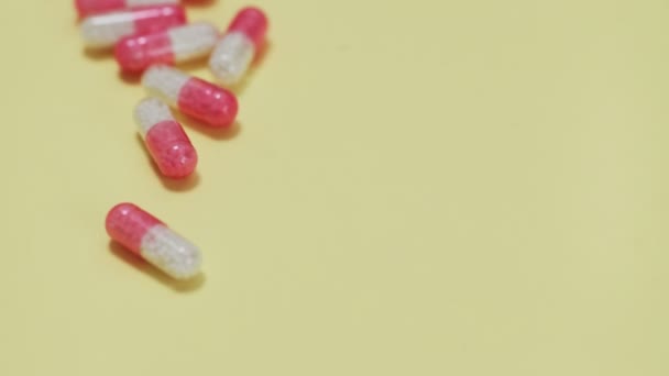Comprimidos rosa e branco com garrafa no fundo amarelo — Vídeo de Stock