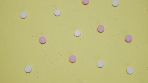 Розовые и белые таблетки на желтом фоне — стоковое видео