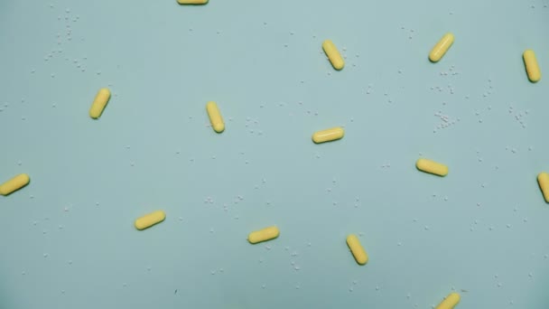 Un montón de pastillas amarillas sobre fondo azul — Vídeo de stock