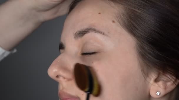 Proces van professionele make-up voor mooie en prachtige vrouw zitten in de Studio. Make-up Artist brengt make-up basis of primer. — Stockvideo