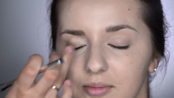 Proces van professionele make-up voor mooie en prachtige vrouw zitten in de Studio. Make-up Kunstenaar brengt concealer op ooglid — Stockvideo