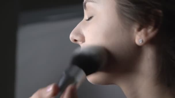 Proces van professionele make-up voor mooie en prachtige vrouw zitten in de Studio. Make-up Kunstenaar brengt poeder met een grote borstel — Stockvideo