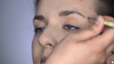 Stüdyoda oturan güzel ve muhteşem kadın için profesyonel makyaj süreci. Makyaj sanatçısı kaşları