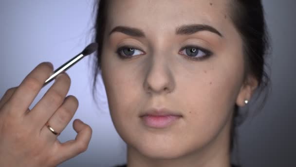 Process av professionell makeup för vacker och vacker kvinna sitter i studion. Make up Artist applicerar rouge med borste på ögonlocket — Stockvideo