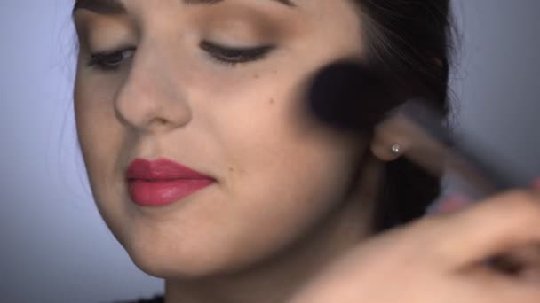 Primo piano di trucco professionale per bella e splendida donna seduta allo Studio. Make up Artist applica la polvere con un grande pennello — Video Stock