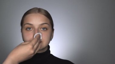 Güzellik stüdyosunda genç bir kadın için profesyonel makyaj yapıyor. Güzel ve doğal bir kadın makyajdan önce pamukla cilt kremi sürüyor.