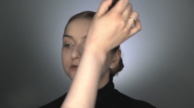 Güzellik stüdyosunda genç bir kadın için profesyonel makyaj yapıyor. Makyaj sanatçısı tozu büyük bir fırçayla uygular