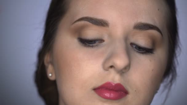 Close up de processo de maquiagem profissional para mulher bonita e linda sentada no estúdio. Maquiagem Artista aplica rímel ao modelo — Vídeo de Stock