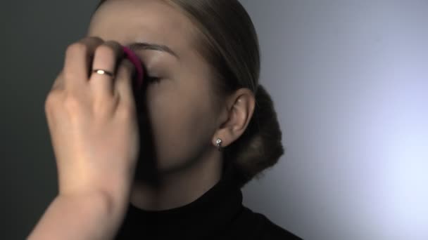 Make-up artist gör professionell make-up för ung kvinna i skönhetsstudio. Make up Artist använder speciell svamp för att applicera concealer i ansiktet — Stockvideo