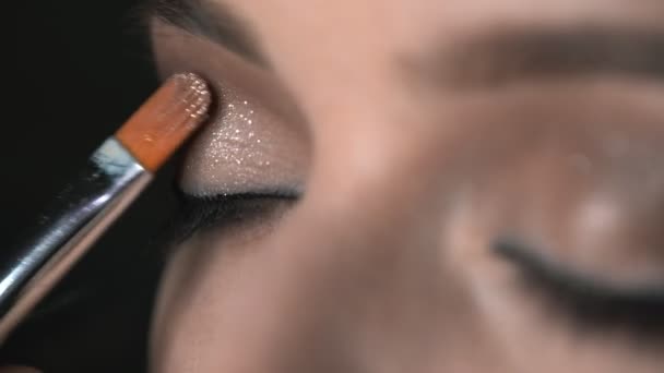 Makro shot makijażu artysty podejmowania profesjonalny makijaż dla młodej kobiety w studio urody. Make up Artist używa pędzla do nakładania brokatu na oczy — Wideo stockowe