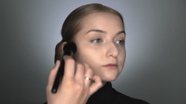 Make-up artist fare make-up professionale per la giovane donna in studio di bellezza. Make up Artist applica la polvere con un grande pennello — Video Stock