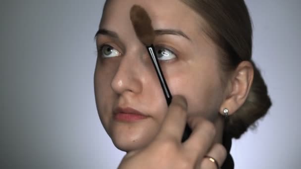 CLose up make-up umělec dělat profesionální make-up pro mladou ženu v kosmetickém studiu. Make-up Artist aplikuje make-up základnu nebo základní. — Stock video