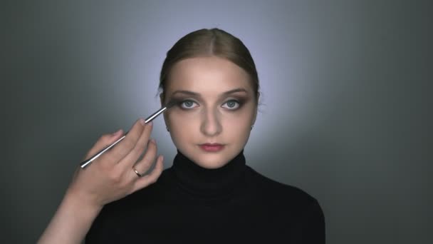 Make-up kunstenaar klaar met het doen van make-up aan jonge vrouw. Mooie vrouw met make-up kijkt naar de camera en poseren — Stockvideo