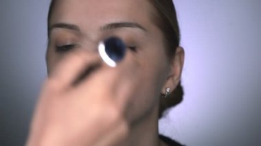 Güzellik stüdyosunda genç bir kadın için profesyonel makyaj yapıyor. Makyaj sanatçısı tozu büyük bir fırçayla uygular