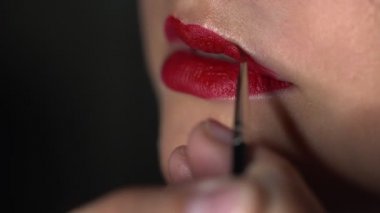 Güzellik stüdyosunda genç bir kadın için profesyonel makyaj yapıyor. Makyaj sanatçısı model üzerine ruj sürüyor
