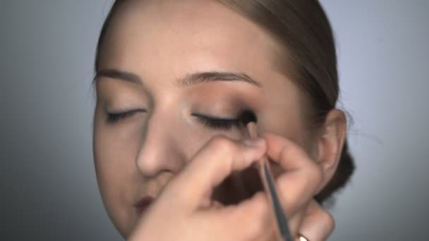 Maquillaje artista haciendo maquillaje profesional para mujer joven en el estudio de belleza. Maquillaje Artista utiliza cepillo para aplicar sombra en el párpado — Vídeos de Stock