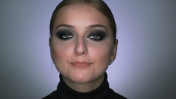 Красивая женщина с макияжем дымящимися глазами позирует перед камерой — стоковое видео