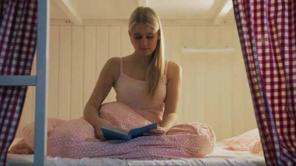 Woman in night underwear finished reading book and going to sleep in cozy hostel room — Stock Video