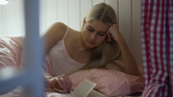 Jovem mulher lendo um livro na acolhedora sala de estar — Vídeo de Stock