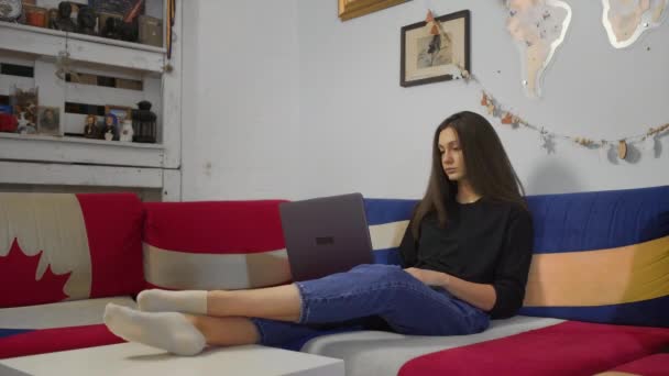 Glückliche junge Frau tippt auf Laptop im Chat in Internet-App sitzen auf dem Sofa zu Hause — Stockvideo