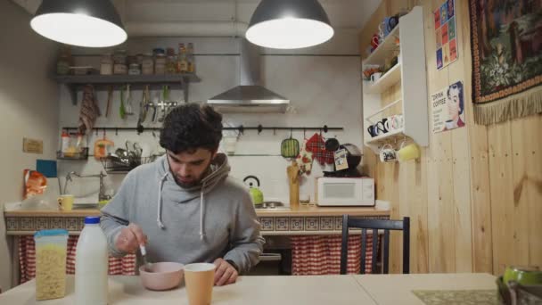 Ein junger Mann frühstückt in der Küche. Mann isst Cornflakes-Getreide — Stockvideo