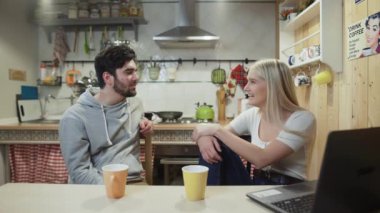 Genç mutlu çift kahvaltıda mutfakta konuşuyor.