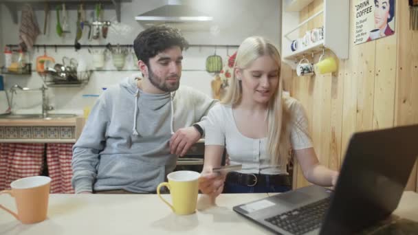 Joven hombre y mujer están haciendo una compra en línea en el cuaderno — Vídeos de Stock