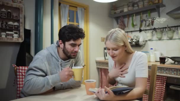 Giovane coppia bere il tè e discutere un libro su una cucina — Video Stock