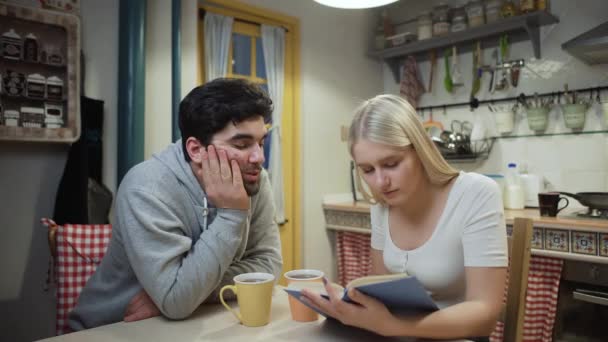 Genç çift çay içip mutfakta kitap tartışır. — Stok video