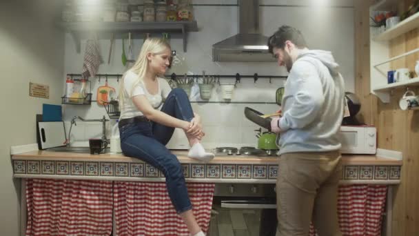 Junger Mann kocht etwas auf Pfanne und seine Frau lacht ihn an — Stockvideo