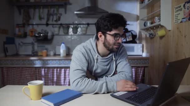 Jovem empresário feliz trabalhando no laptop na cozinha em casa à noite — Vídeo de Stock