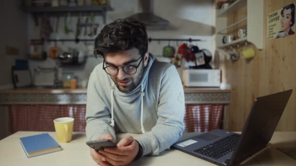 Giovane uomo felice utilizzando smartphone in cucina a casa di notte — Video Stock