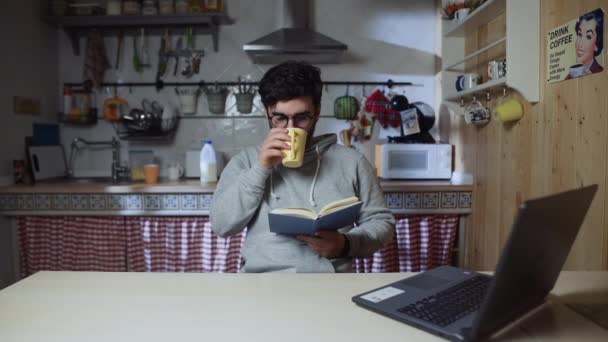 Jovem lendo um livro na cozinha em casa à noite — Vídeo de Stock