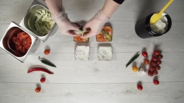 Profesyonel şefin en iyi görüntüsü fast food restoranında lezzetli bir hamburger pişirir. Eldivenli kadın aşçı hamburgerlere lahana koyar.