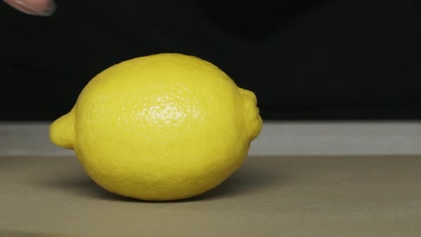 Chef händer i handskar skära en citron på hackbrädan. Handskivad citron på tavlan närbild. Saftig citron skuren i skivor. Den vassa kockkniven skär citrusfrukten. — Stockvideo