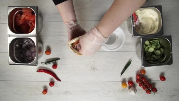 Vue du dessus des mains du chef professionnel dans les gants faisant shawarma dans le pain. Chef en gants met l'oignon mariné dans shawarma 
