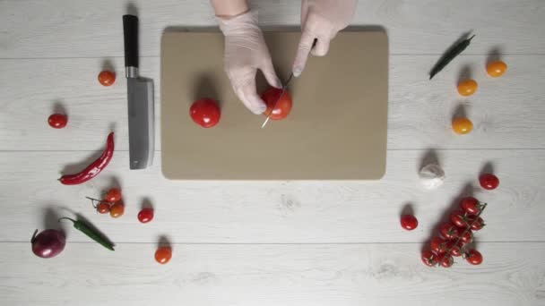 Шеф-кухар розрізає помідори на пластиковій дошці зверху — стокове відео