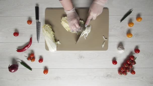 Chef coupe le chou chinois sur une planche de plastique vue du dessus — Video