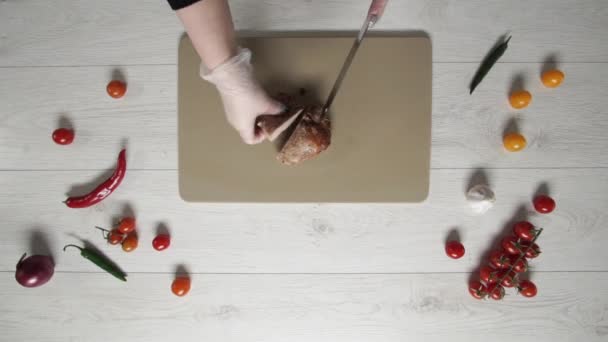 Chef coupe le rôti de porc sur une planche de plastique vue du dessus 