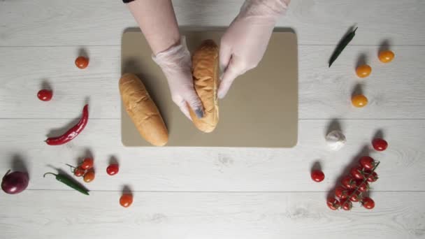 Bovenaanzicht van chif snijdt wit hot dog brood mee. Koken hot dog — Stockvideo