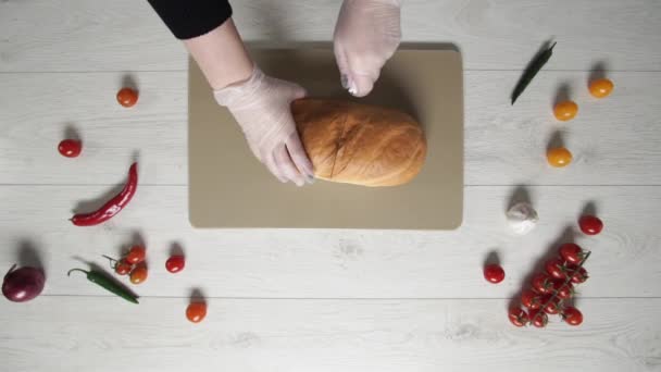 Draufsicht auf das Schneiden von frischem Brot auf einem Schneidebrett aus Kunststoff. — Stockvideo