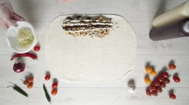 Beyaz eldivenli aşçı donör kebabına lahana koyar. Pide veya lavaşta shawarma. Tavuk, patates kızartması, peynir ve sebzeli shawarma pişiriyorum.