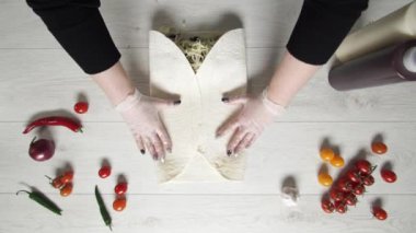 Şefin beyaz eldivenli üst görüntüsü kebapçı kebabı pide veya lavda. Tavuk, patates kızartması, peynir ve sebzeli shawarma pişiriyorum.