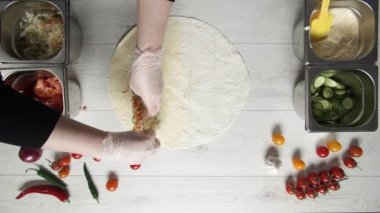 Beyaz eldivenli aşçı donör kebabına lahana koyar. Pide veya lavaşta shawarma. Tavuk, patates kızartması, peynir ve sebzeli shawarma pişiriyorum.